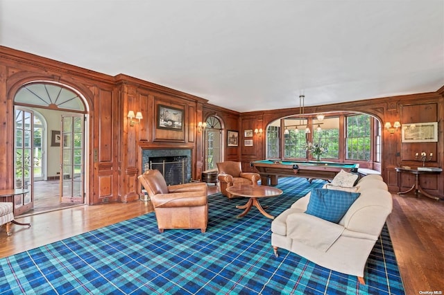 living room featuring french doors, wooden walls, a premium fireplace, pool table, and wood-type flooring