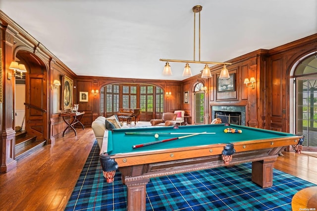 recreation room featuring ornamental molding, wooden walls, dark wood-type flooring, billiards, and a fireplace