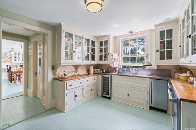 kitchen featuring wine cooler, white cabinetry, hanging light fixtures, and light hardwood / wood-style floors