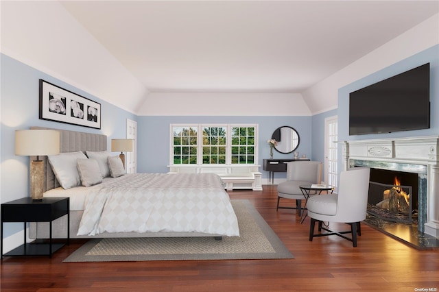 bedroom with hardwood / wood-style floors, lofted ceiling, and a fireplace