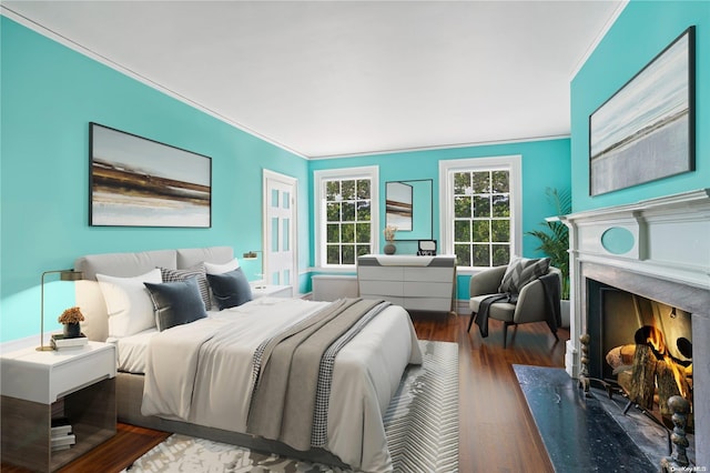 bedroom featuring crown molding, dark wood-type flooring, and a high end fireplace