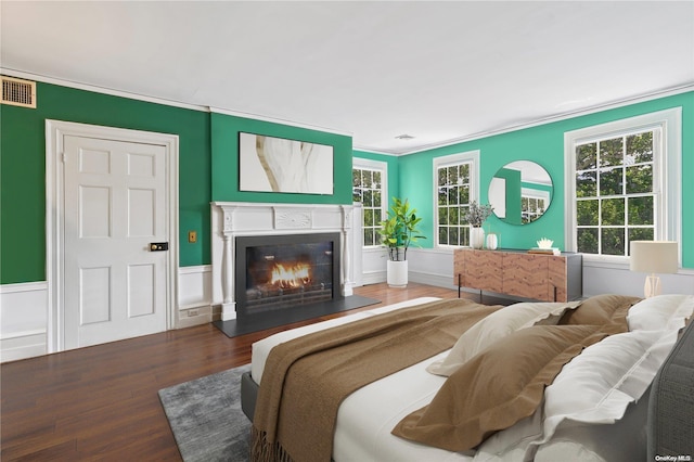 bedroom featuring dark hardwood / wood-style floors, ornamental molding, and multiple windows