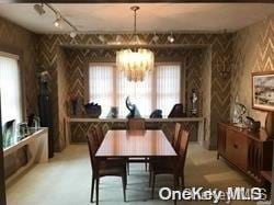 dining area with track lighting and an inviting chandelier