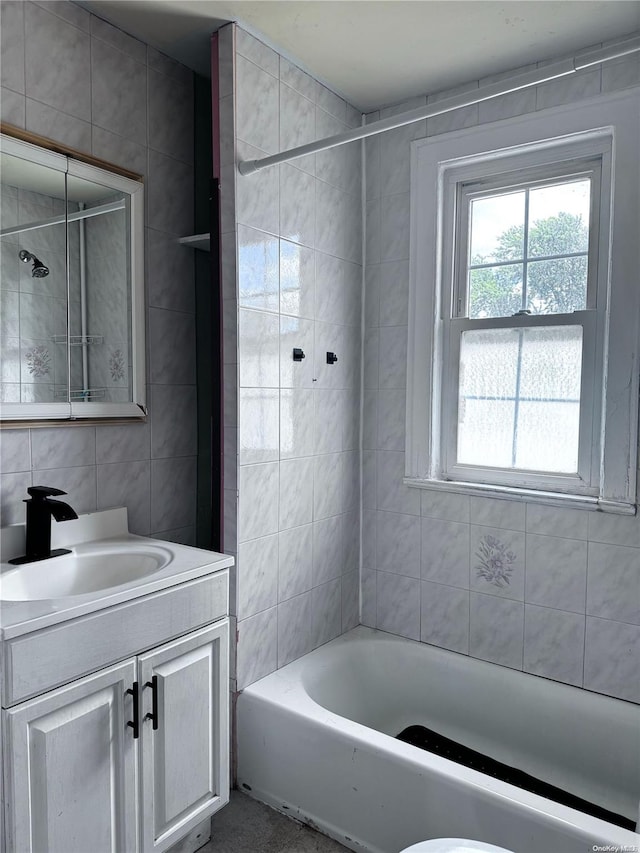 full bathroom with tiled shower / bath combo, vanity, decorative backsplash, tile walls, and toilet