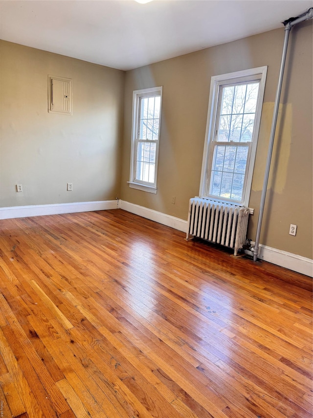 unfurnished room with light wood-type flooring, a wealth of natural light, and radiator heating unit