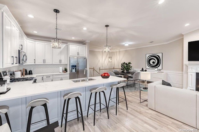 16 Ocean Watch Ct Unit 16, Freeport, NY 11520 - kitchen with stainless steel appliances, ornamental molding, a sink, white cabinetry, and a kitchen breakfast bar