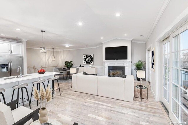 16 Ocean Watch Ct Unit 16, Freeport, NY 11520 - living room with ornamental molding, light wood-type flooring, vaulted ceiling, a fireplace, and recessed lighting