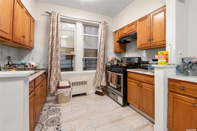 kitchen featuring backsplash, stainless steel gas range oven, and radiator heating unit