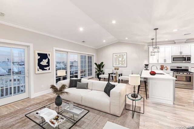 living room featuring light wood-type flooring, vaulted ceiling, crown molding, sink, and a notable chandelier