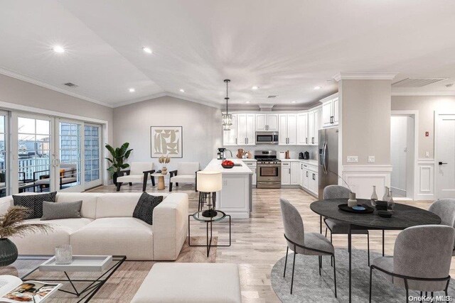 living room with light wood-type flooring, vaulted ceiling, ornamental molding, and sink