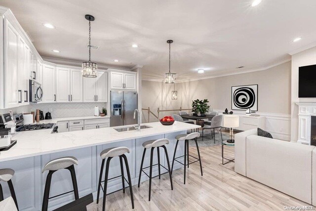 kitchen with white cabinets, light wood-type flooring, decorative light fixtures, kitchen peninsula, and stainless steel appliances