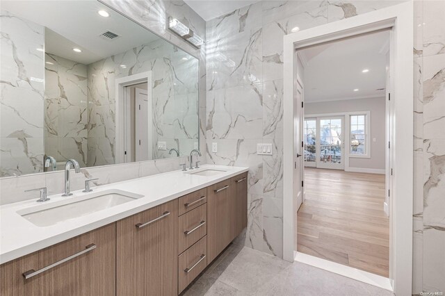 bathroom featuring wood-type flooring, vanity, tile walls, and ornamental molding