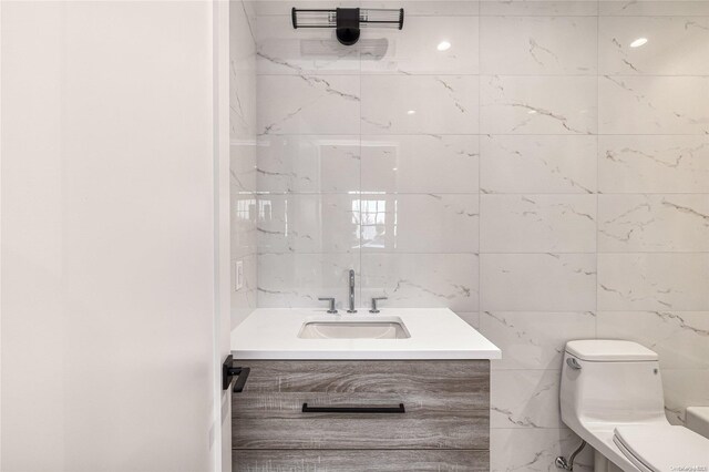 bathroom with vanity, tile walls, and toilet