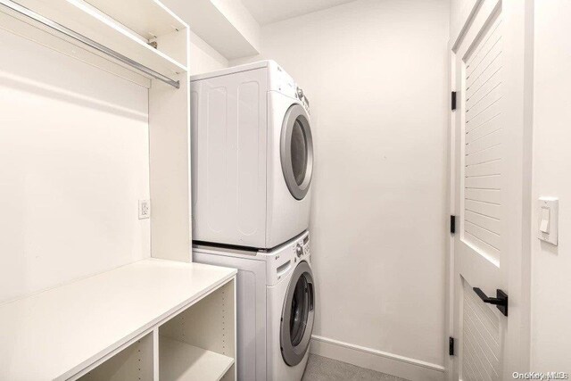 clothes washing area featuring stacked washing maching and dryer