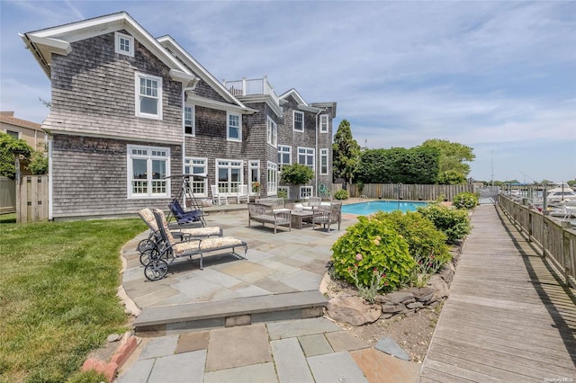 rear view of property with a fenced in pool, a patio area, and a lawn