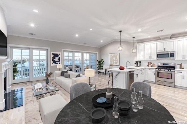 dining area with light hardwood / wood-style floors, sink, lofted ceiling, and crown molding