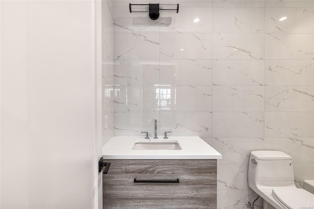 bathroom featuring vanity, tile walls, and toilet