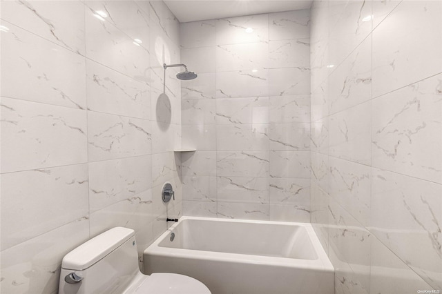 bathroom featuring tiled shower / bath combo, toilet, and tile walls