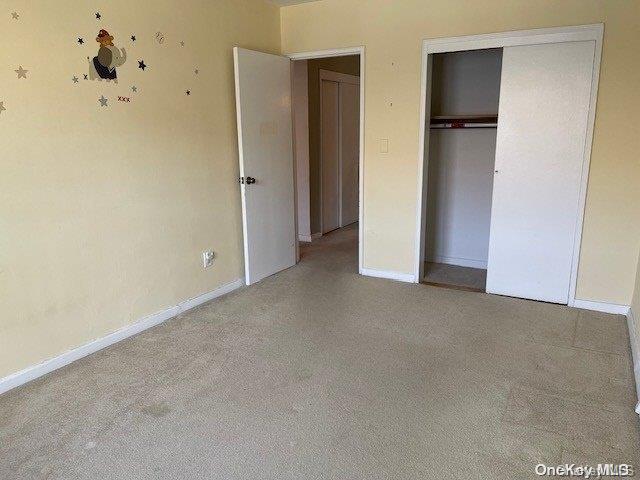 unfurnished bedroom with a closet and light colored carpet