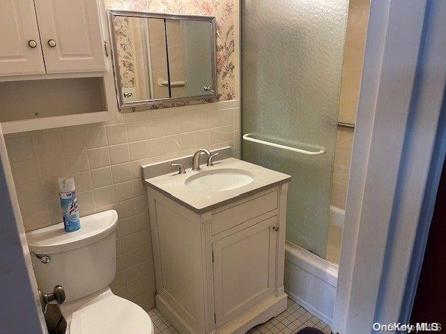 bathroom featuring tile patterned floors, vanity, tile walls, and toilet