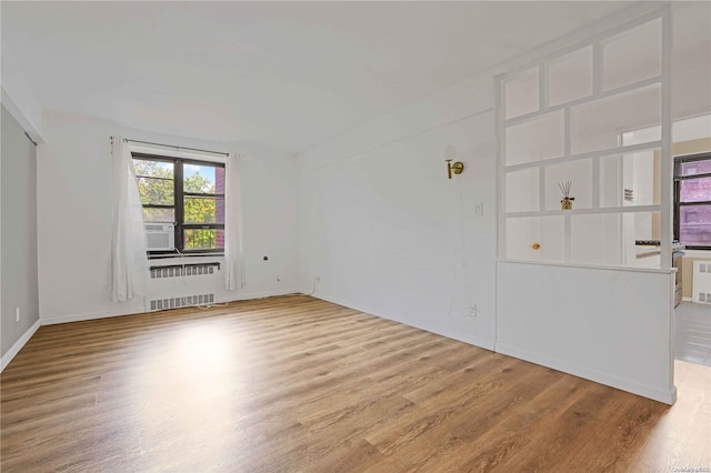 spare room with hardwood / wood-style flooring, cooling unit, and radiator heating unit