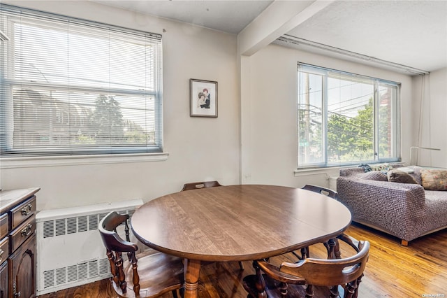 dining room featuring beamed ceiling, radiator heating unit, and light hardwood / wood-style flooring