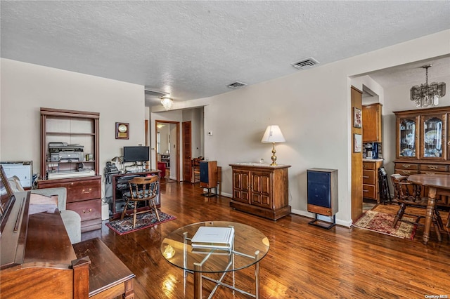 living room with a notable chandelier, dark hardwood / wood-style flooring, and a textured ceiling