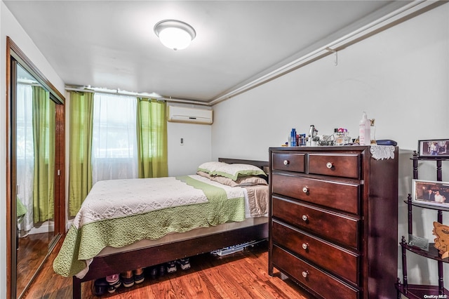 bedroom with hardwood / wood-style flooring and a wall unit AC