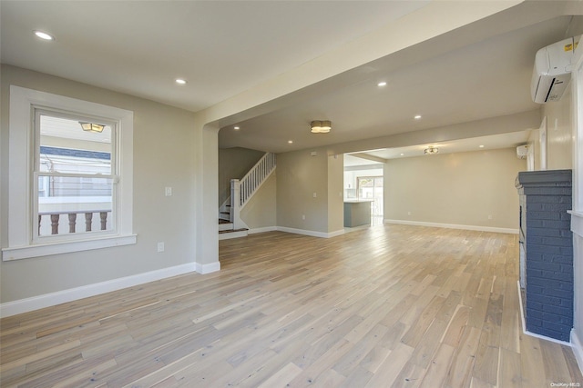 unfurnished living room featuring a wall mounted air conditioner, light hardwood / wood-style floors, and a fireplace