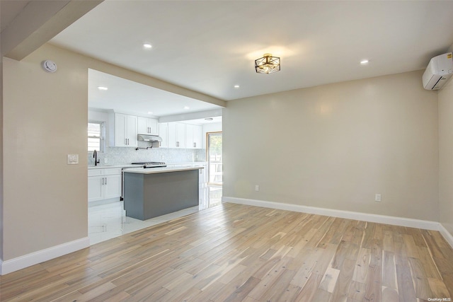 interior space featuring light wood-type flooring, a wall unit AC, a healthy amount of sunlight, and sink