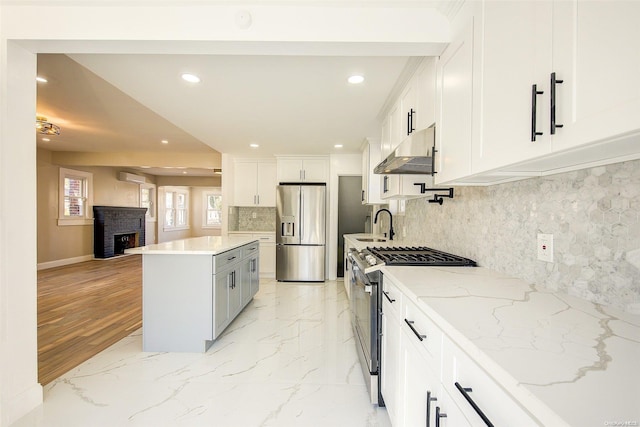 kitchen with a kitchen island, light stone countertops, white cabinetry, and stainless steel appliances