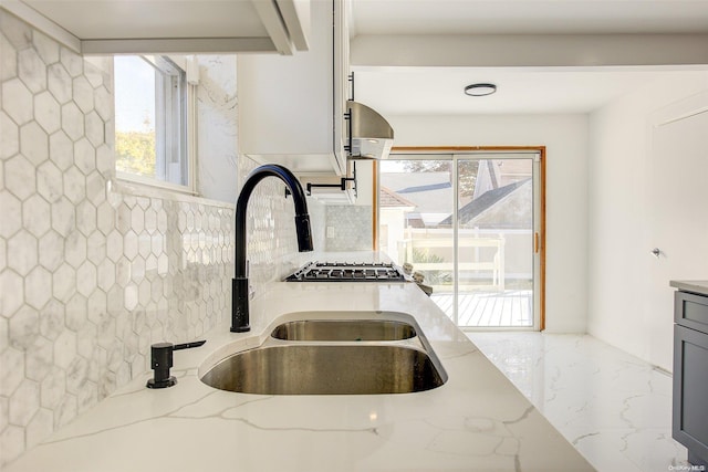 kitchen with decorative backsplash, light stone countertops, and sink