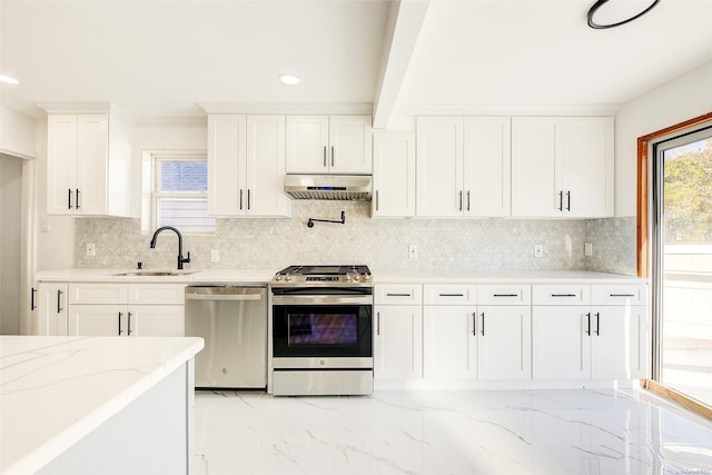 kitchen with white cabinets, sink, appliances with stainless steel finishes, tasteful backsplash, and light stone counters