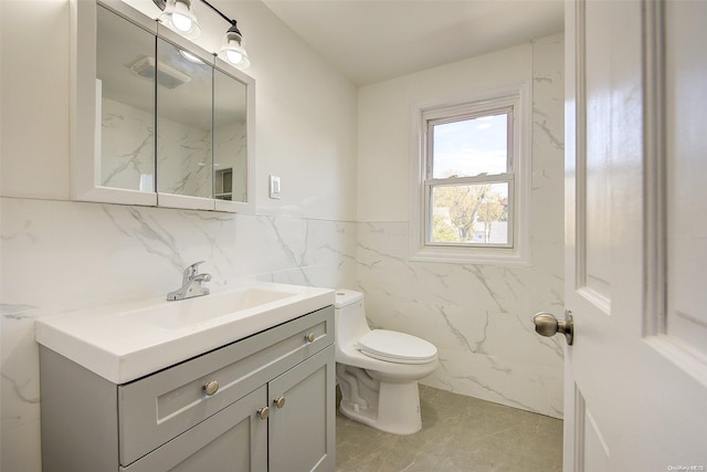 bathroom with tile patterned floors, vanity, toilet, and tile walls