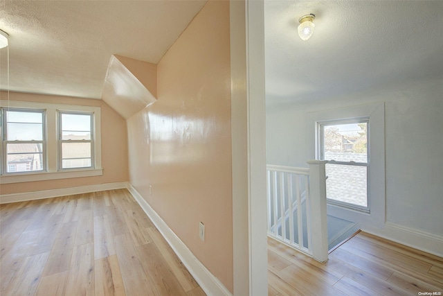 additional living space with light hardwood / wood-style flooring and a textured ceiling