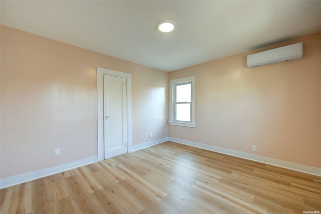 empty room with light hardwood / wood-style floors and an AC wall unit