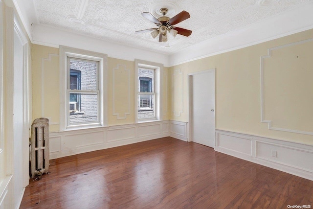 empty room with ceiling fan, radiator heating unit, dark wood-type flooring, and a textured ceiling