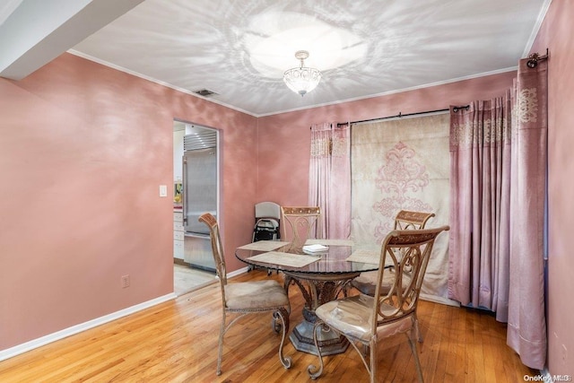 dining room with hardwood / wood-style floors, ornamental molding, and an inviting chandelier