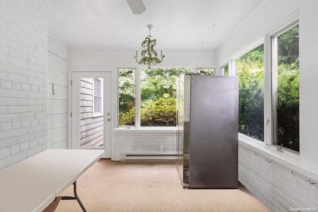 sunroom featuring an inviting chandelier and a baseboard heating unit