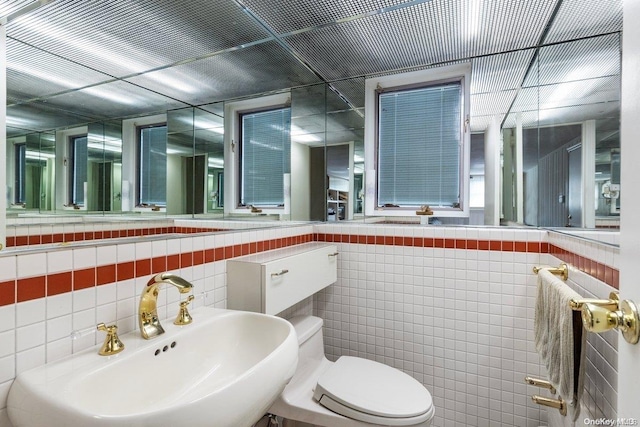 bathroom featuring toilet, sink, and tile walls