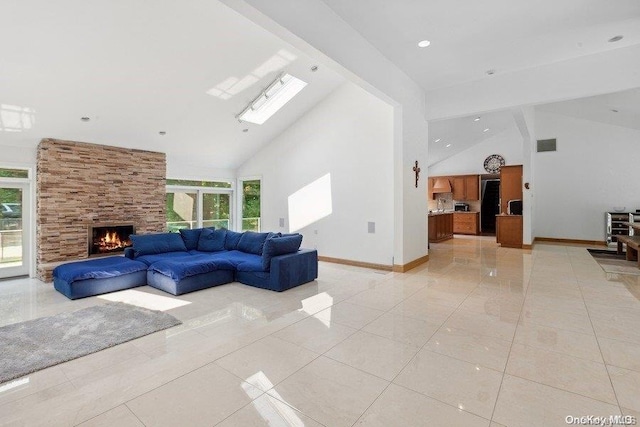 living room featuring a stone fireplace, light tile patterned flooring, high vaulted ceiling, and a skylight