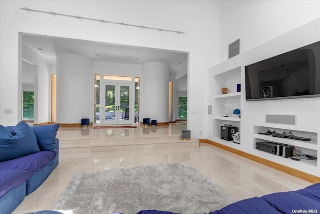 tiled living room featuring built in shelves, rail lighting, and french doors