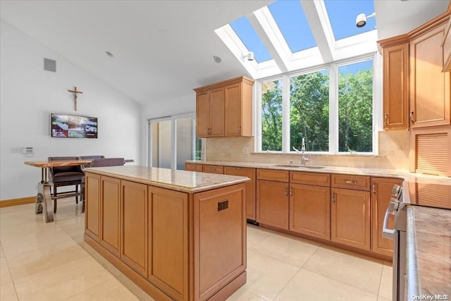 kitchen with sink, a center island, tasteful backsplash, stainless steel range oven, and vaulted ceiling with skylight