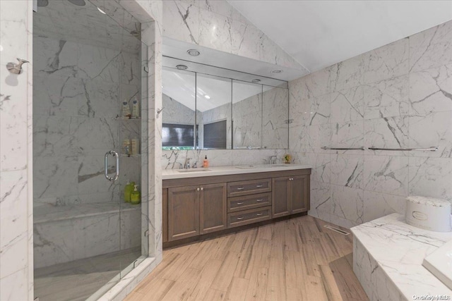 bathroom featuring vanity, vaulted ceiling, a shower with door, tile walls, and hardwood / wood-style floors