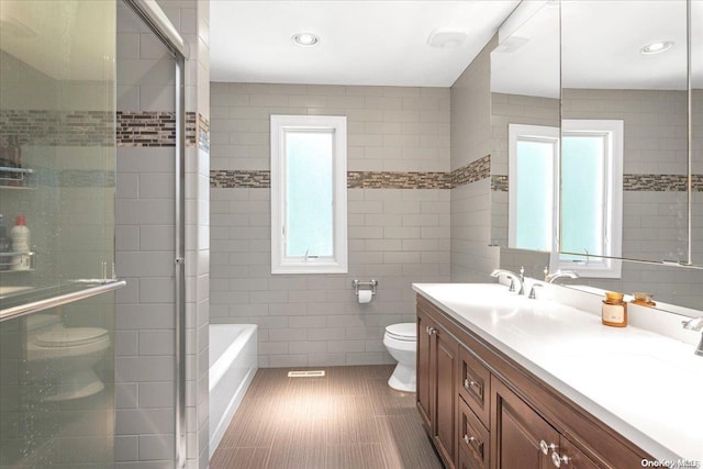 full bathroom featuring vanity, toilet, tile walls, and independent shower and bath