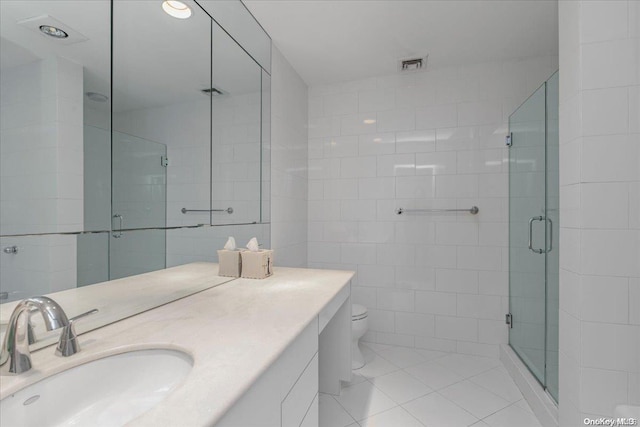 bathroom featuring vanity, tile patterned flooring, toilet, walk in shower, and tile walls