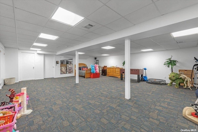 basement with a paneled ceiling and dark carpet