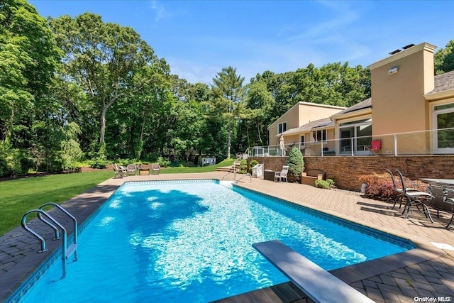 view of pool featuring a diving board, a yard, and a patio