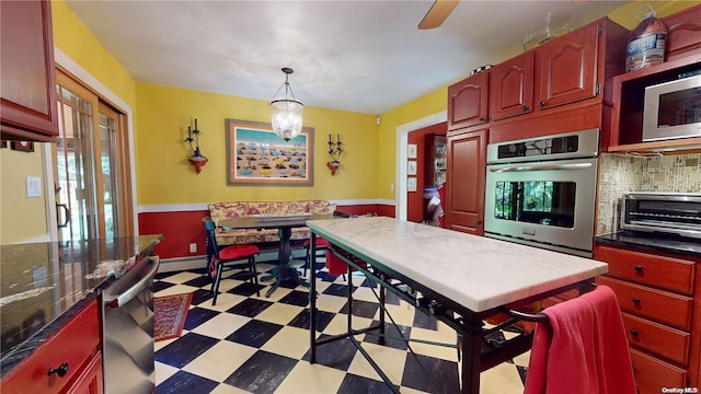 kitchen with pendant lighting, baseboard heating, appliances with stainless steel finishes, tasteful backsplash, and a chandelier