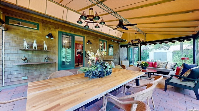 sunroom / solarium with ceiling fan with notable chandelier and vaulted ceiling